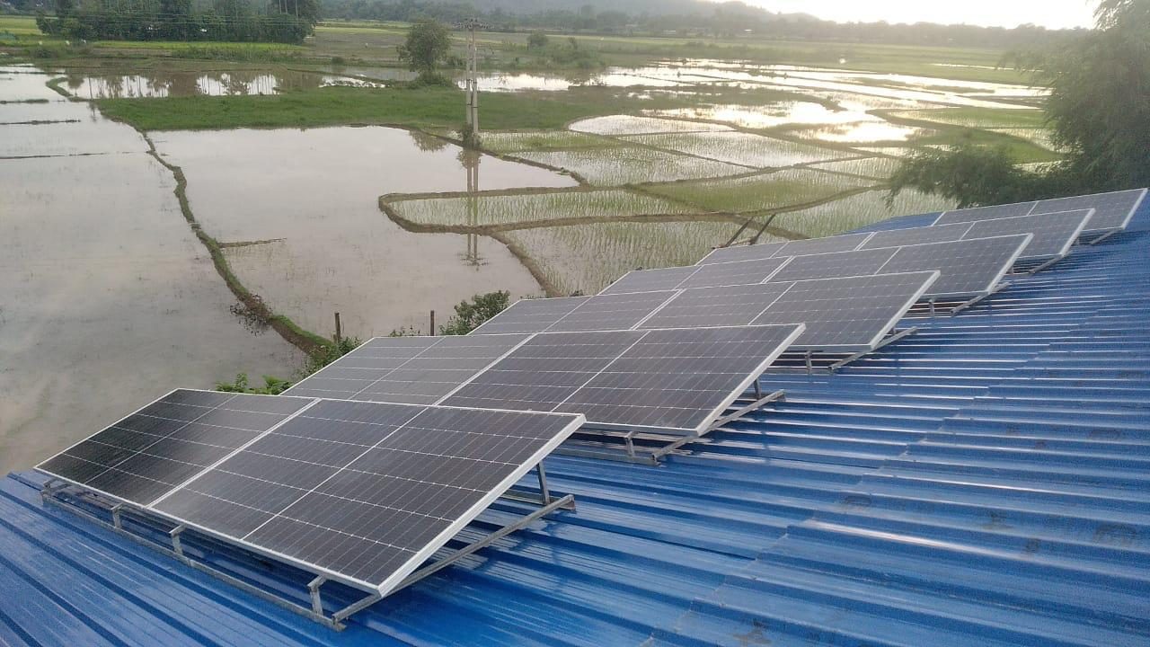 Rooftop solar array installed by Zenergy Greens overlooking paddy fields in Assam